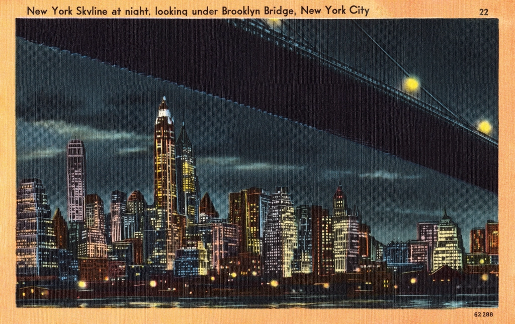 Vintage postcard: the New York skyline lit up at night under the Brooklyn Bridge